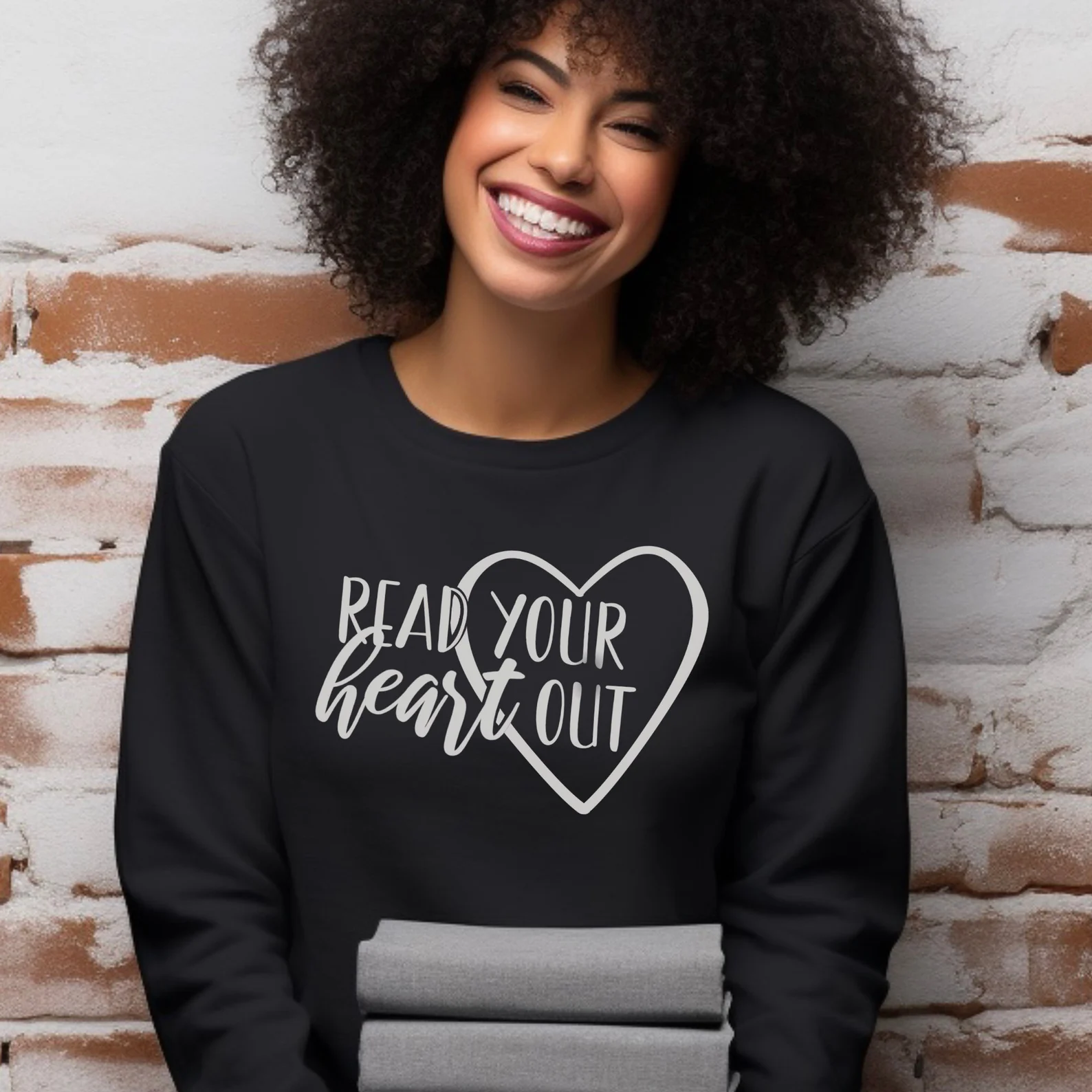 image of a Black woman modeling a black sweatshirt with white text that says "read your heart out." 