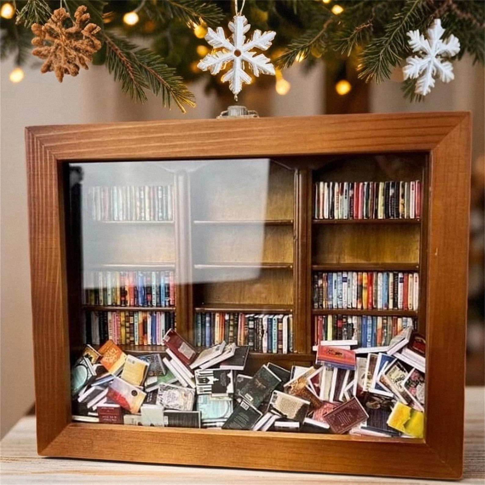 Mini bookshelf with books on shelves and in piles in front of shelf behind glass in front of snowflake background. 