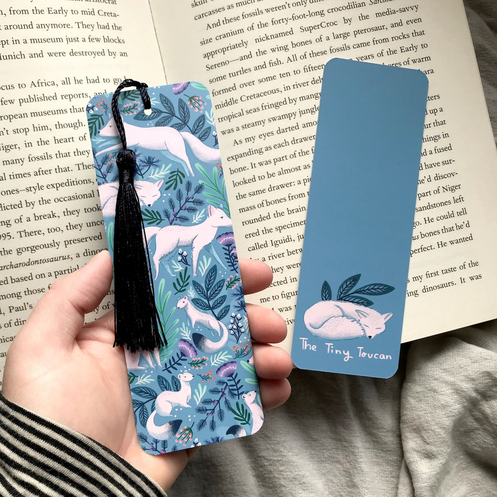 A blue bookmark depicting white foxes against a blue floral background