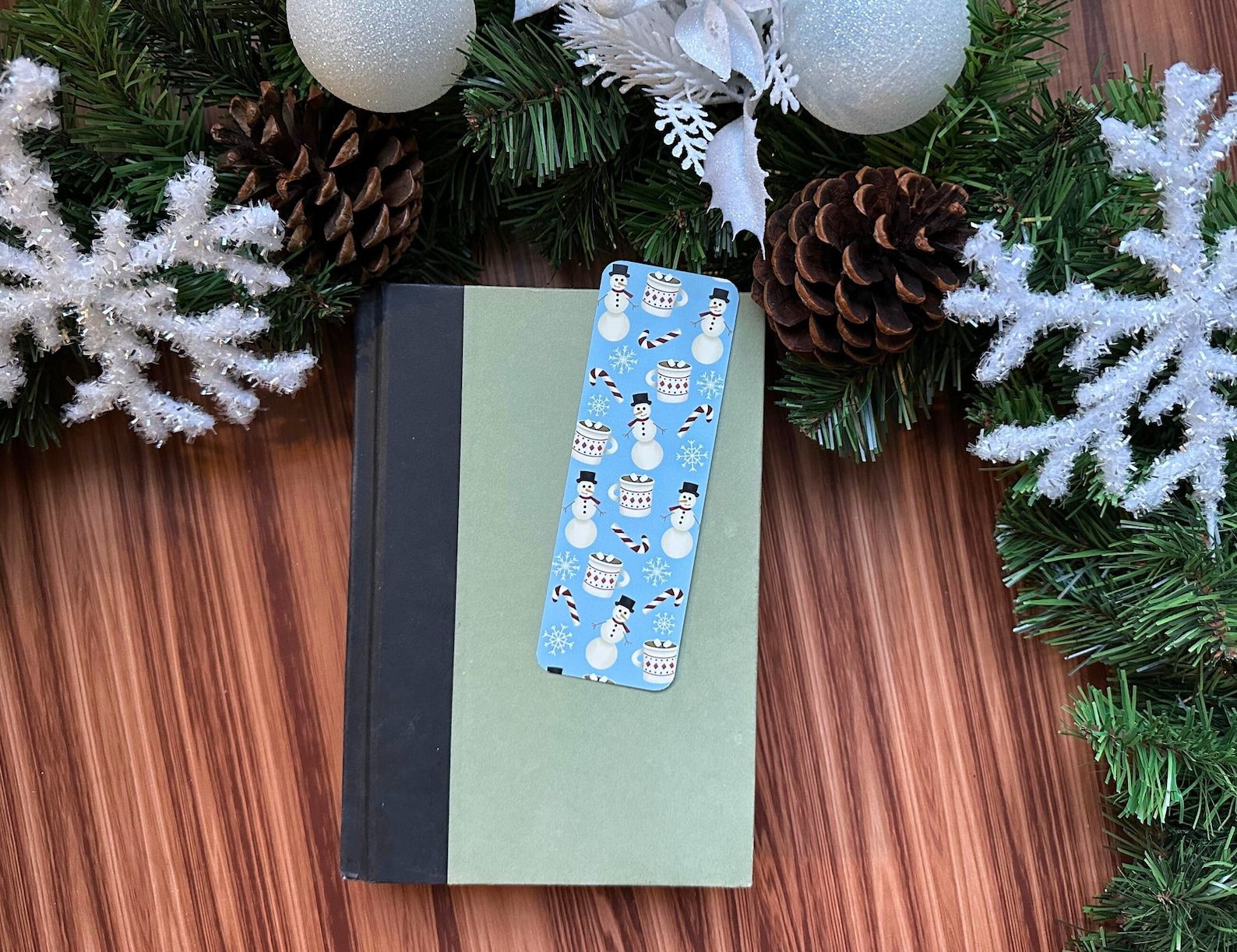 A black, white, and blue aesthetic bookmark with snowmen, candy canes, and hot cocoa