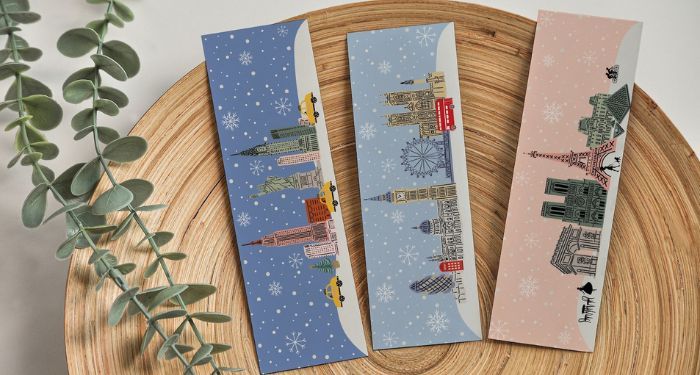 three winter bookmarks arranged on a woodcut next to a branch of eucalyptus