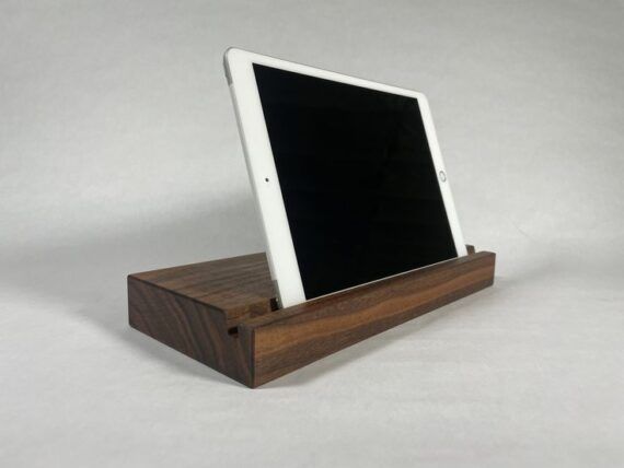 a dark wood plack with a slot that holds a white ipad 