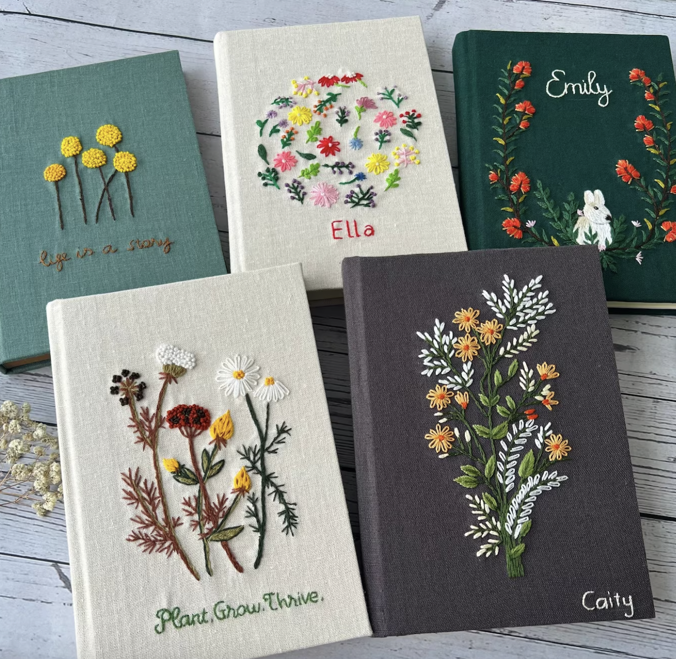 Image of five linen-covered notebooks with hand-embroidered floral designs
