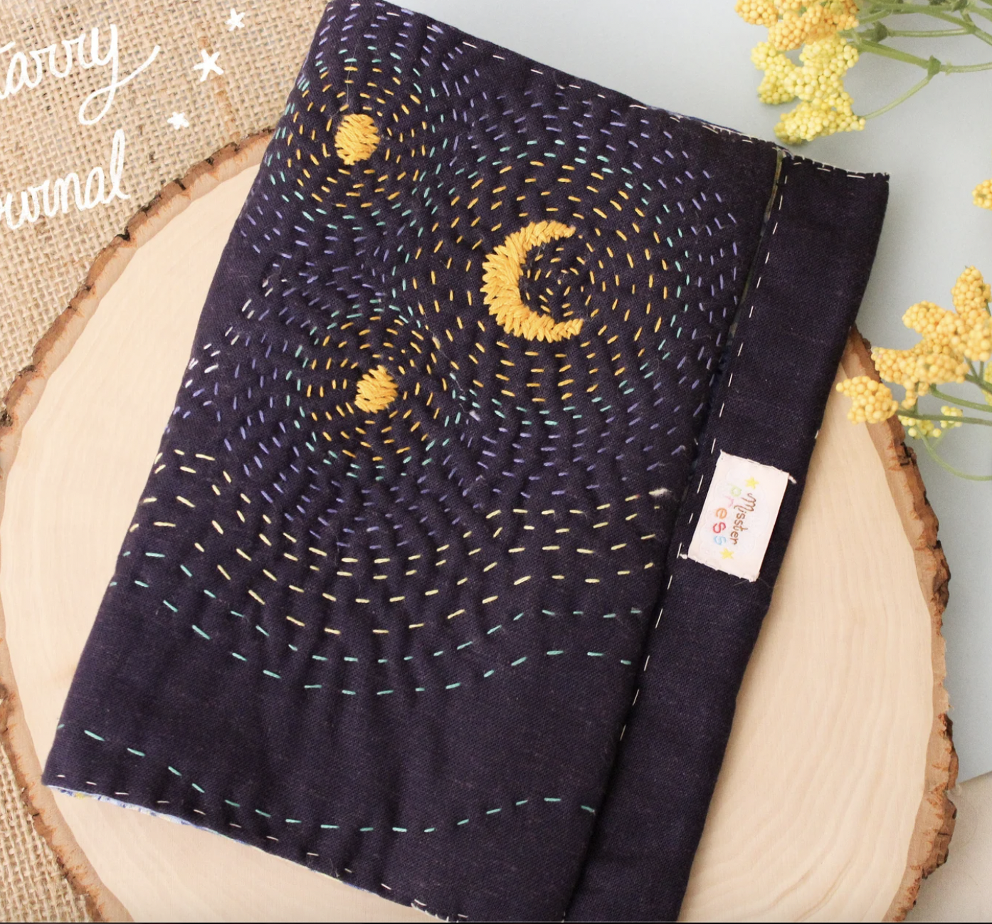 Image of a dark blue fabric book cover embroidered with stars and a crescent moon