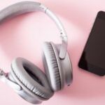 Image of headphones and a phone on aa pink background