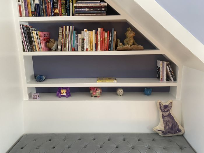 a set of bookshelves behind a cushioned bench
