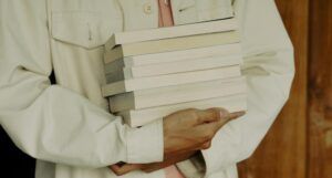 a closeup photo of someone carrying a stack of books