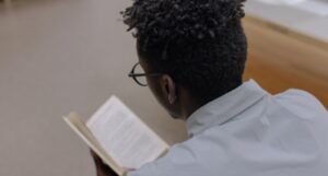 dark brown-skinned man reading a books; pic from the bac
