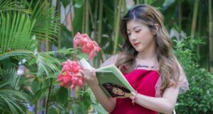 light-skinned Asian woman reading a book in a garden