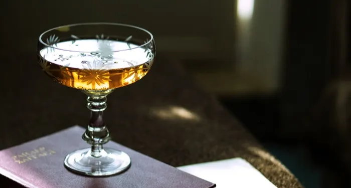 a cocktail glass full of liquor, sitting atop a book