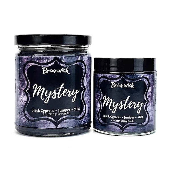 Two candles from a company called Briarwick, one larger than the other, Both contain purple and black labels and the name "Mystery"