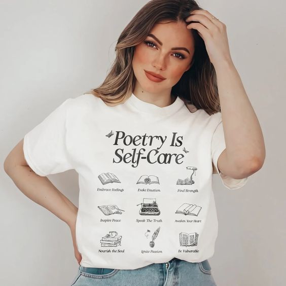 a white tshirt with all black printing. In large letters it says "poetry is self care," and smaller icon images with text below are laid out in a grid format.