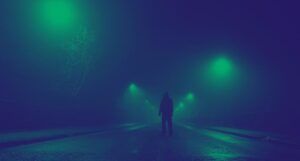 hooded figure standing in the middle of a highway. the image has a black and green filter applied