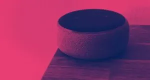 a smart speaker on the edge of a wood surface. a dark red filter is applied to the image