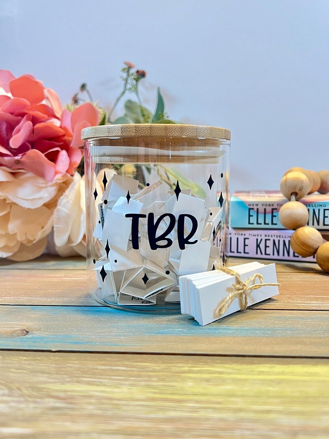 Clear jar with a stencil that says TBR surrounded by stars. Jar is filled with folded sips of paper.