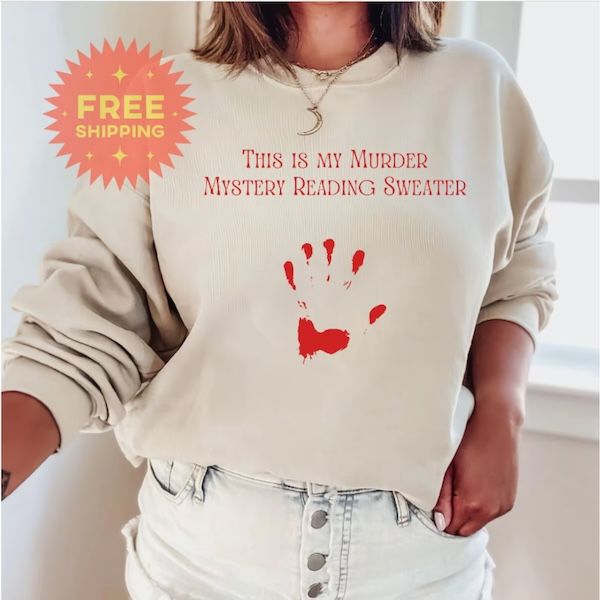 cream-colored crewneck with a red handprint and red text that reads "This is My Murder Mystery Reading Sweater"