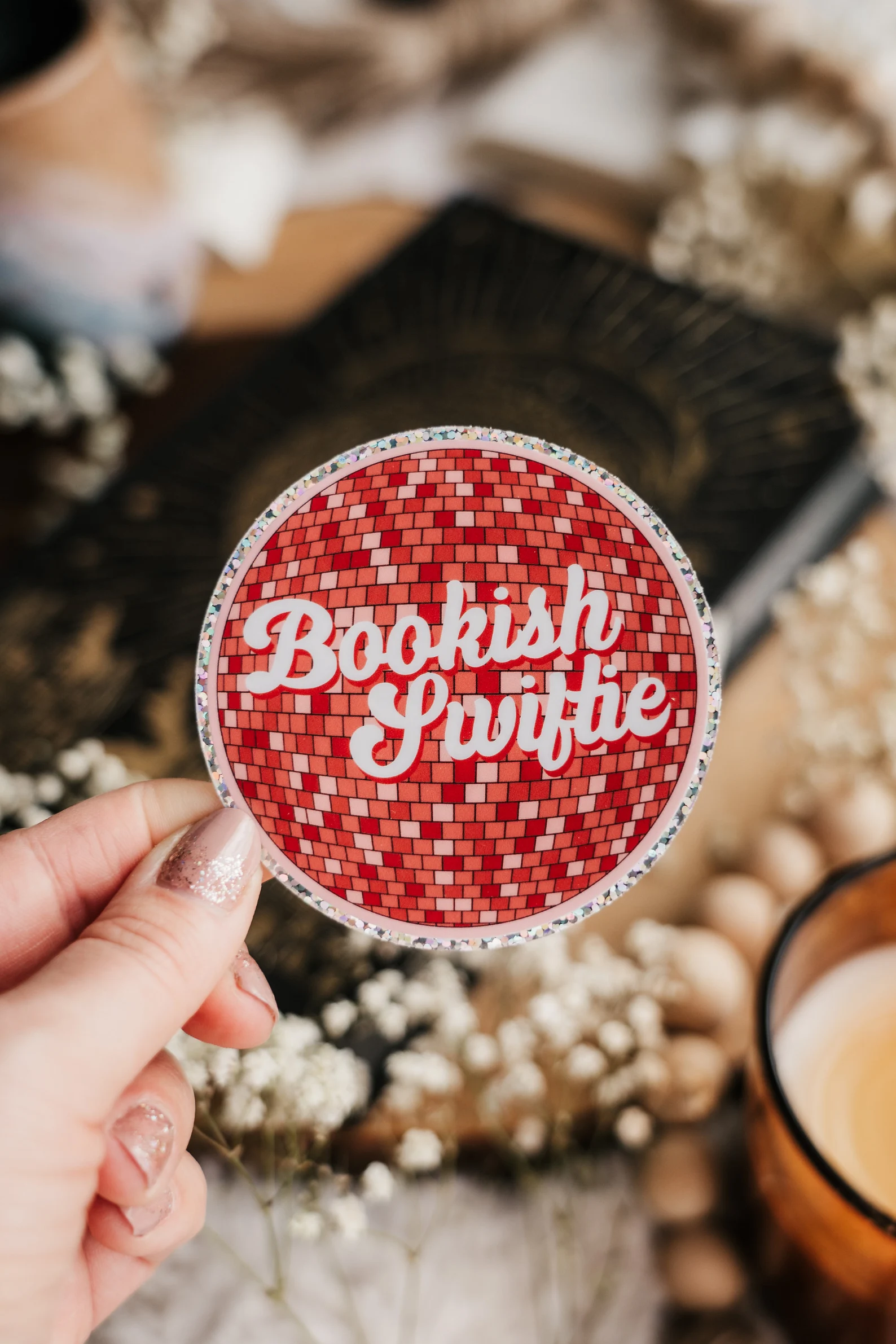 Image of a pink mirror ball sticker that says "bookish swiftie."