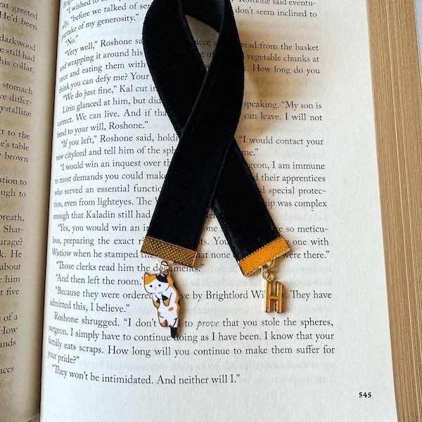 velvet ribbon bookmark. a cat charm hangs form one end, and the letter H on the other