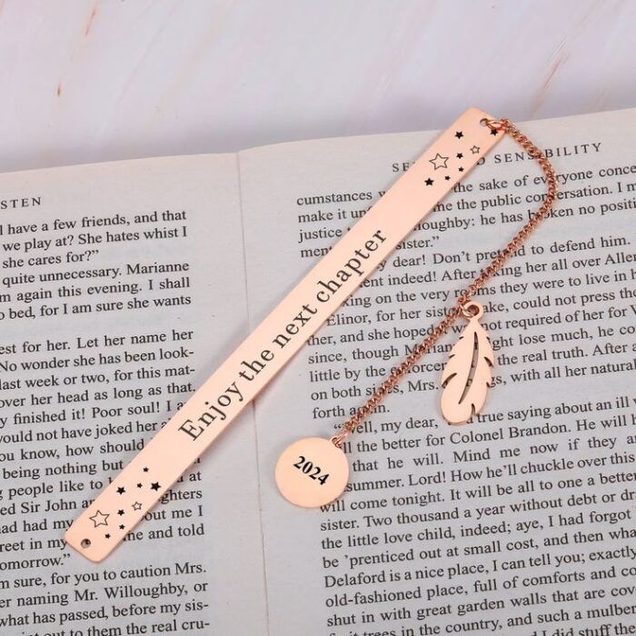 a copper bookmark with the words "enjoy the next chapter" with a dangling charm that has a year engraved