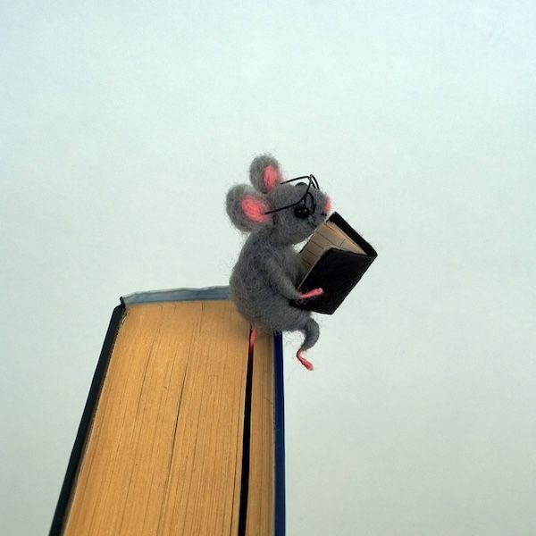 a felt mouse bookmark where the mouse, who is holding a book, appears to be perched on the top of a book