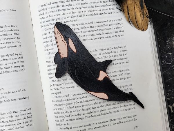 an orca bookmark made of leather inside an ope book
