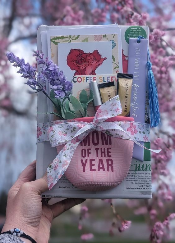 image of a drink koozy that says mom of the year with candies and flowers peeking out the top, all laying on top of a book 