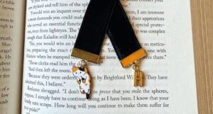 velvet ribbon bookmark. a cat charm hangs form one end, and the letter H on the other