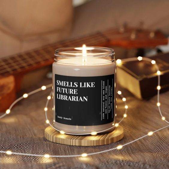 a white candle with a black label that reads "smells like future librarian"