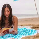 Asian woman reading a book on the beach