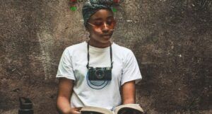 brown-skinned Black woman reading with a camera around her neck