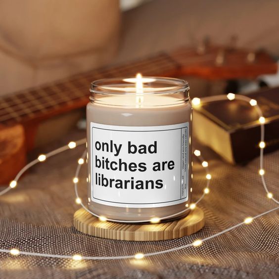 a cozy room with soft white lights and a lit white candle with the words "only bad bitches are librarians."
