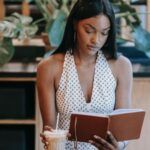 brown-skinned Black woman reading a book in a cafe