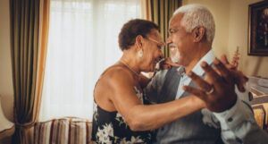Image of an elderly Black couple dancing in a living room
