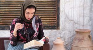 light-skinned woman reading in a head scarf