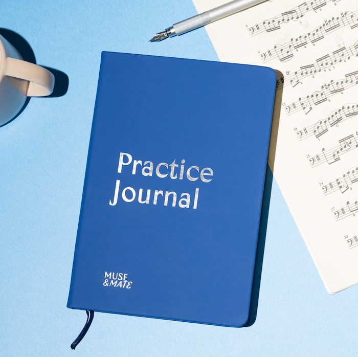 cover of Muse and Mate practice journal with sheet music in background