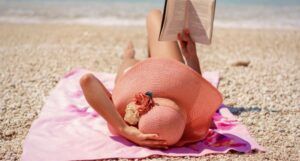 a fair-skinned person reading on the beach