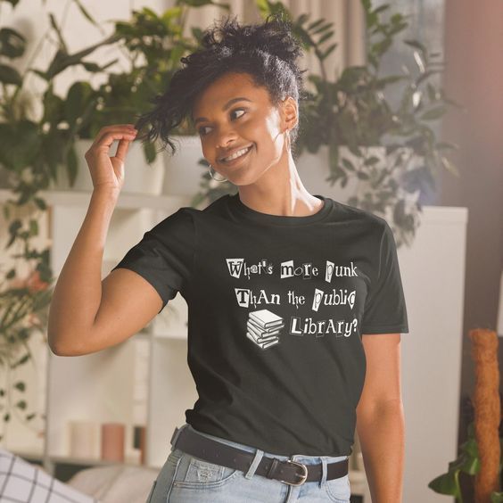a black woman looking to the side and smiling wearing a black tshirt that says "What's more punk than the public library?"