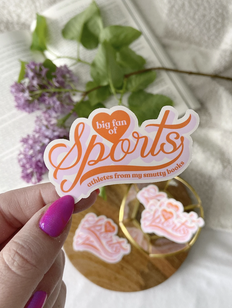 Pink and orange vinyl sticker that says "big fan of sports" and in smaller letters "athletes in my smutty books"