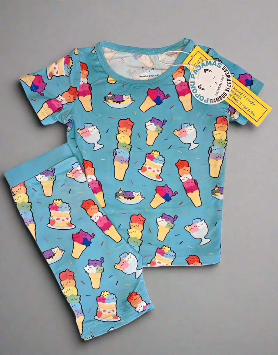 Image of kid size pajamas with ice cream scoops that are cat faces. Those scoops are rainbow flag colors. 
