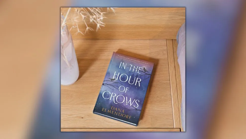 The book In The Hour Of Crows by Dana Elmendorf on hardwood floor