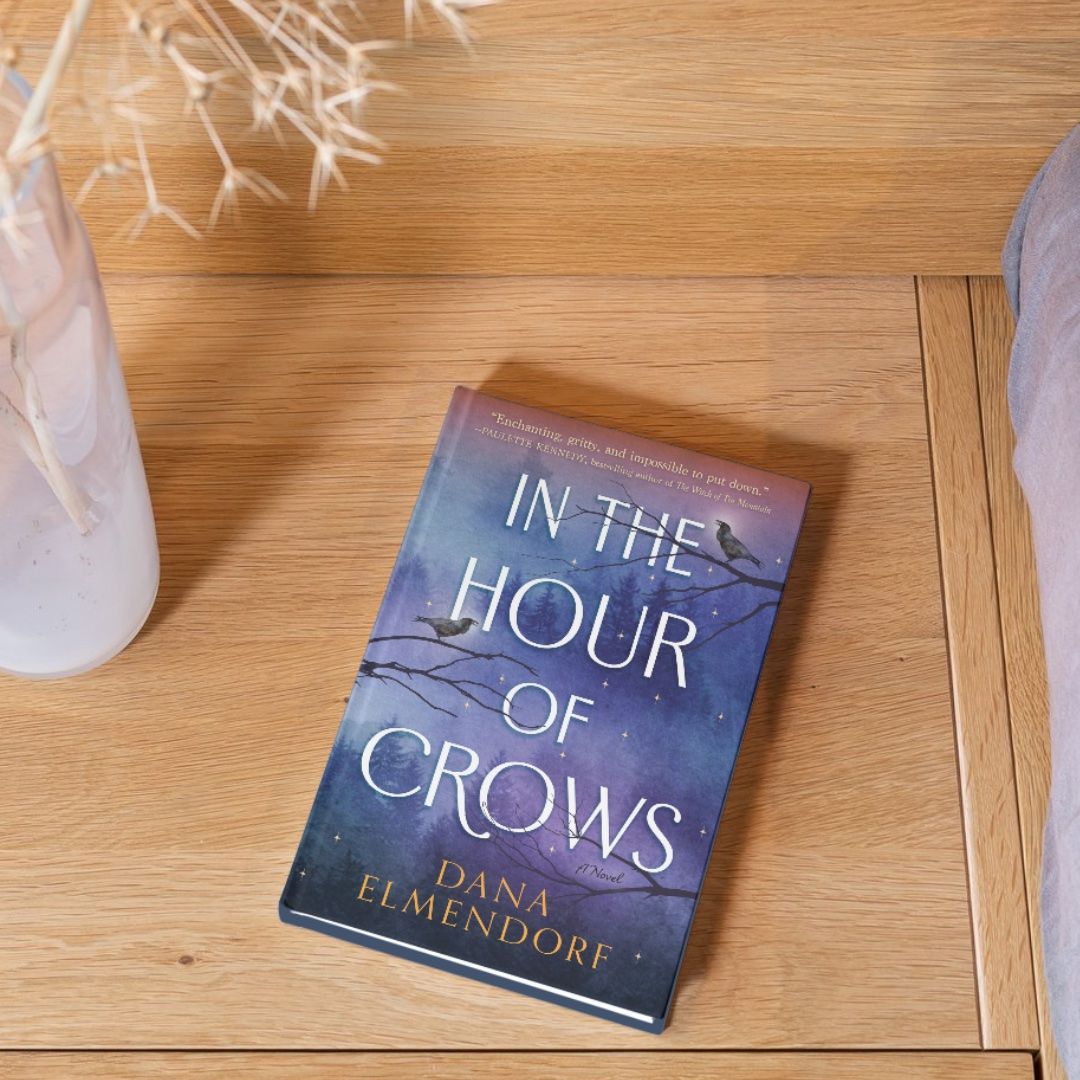 The book In The Hour Of Crows by Dana Elmendorf on hardwood floor