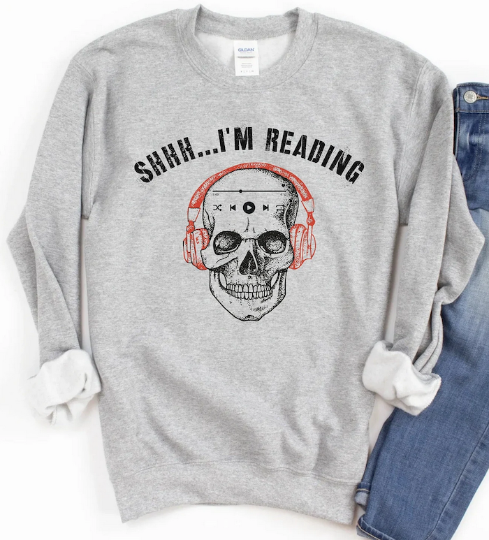 a grey sweatshirt with a skull wearing headphones graphic illustration that says "shhh...I'm reading"