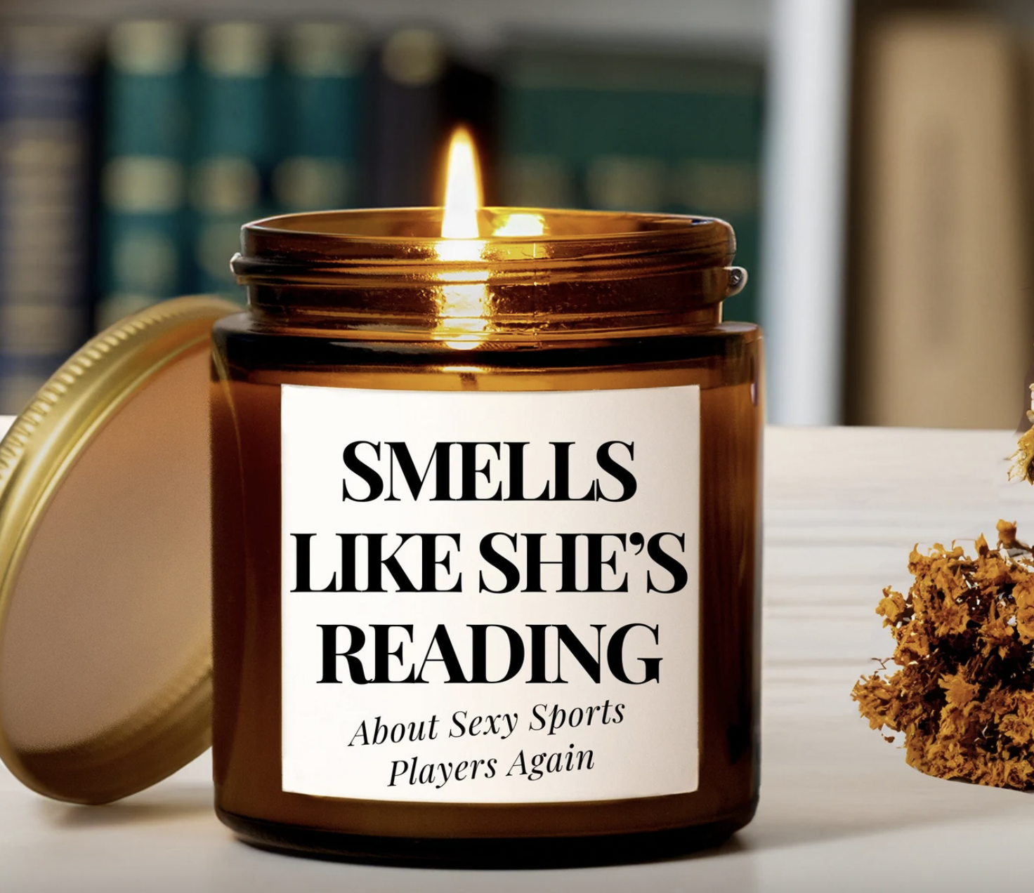 image of a candle in an amber glass jar with a label that says "smells like she's reading about sexy sports players again"