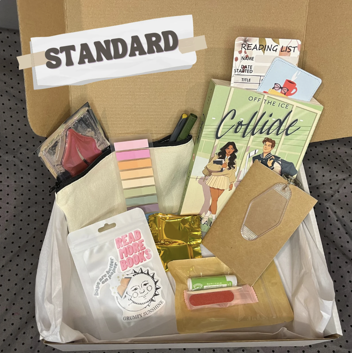 image of a "blind date with a sports romance book" box with the book Collide, various annotation tools, stickers, and a keychain