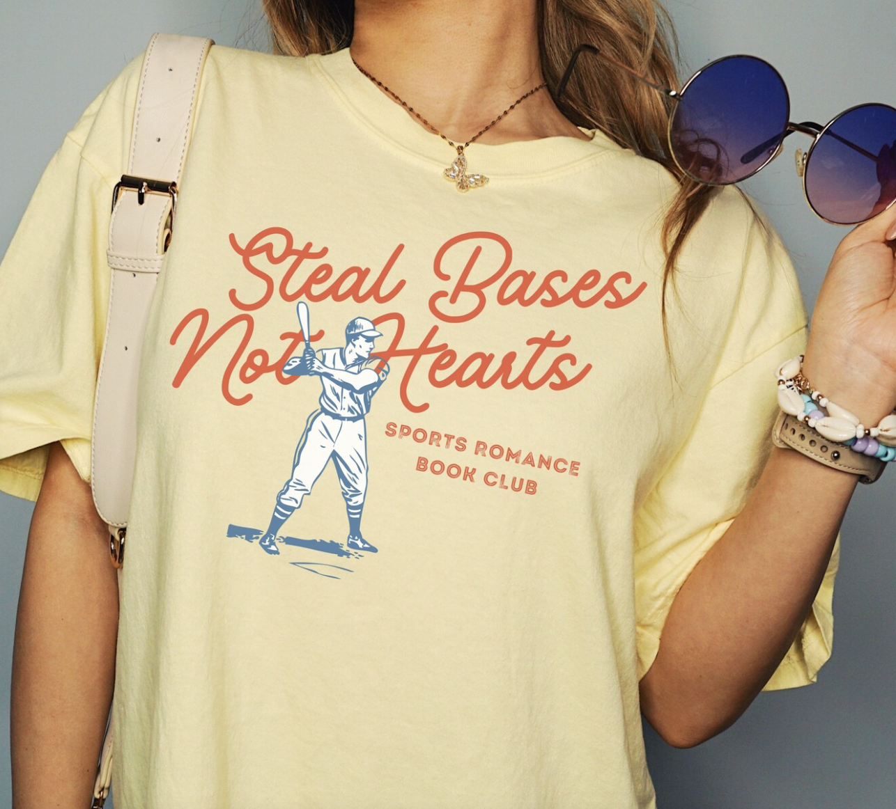 photo of a yellow t-shirt with a baseball player illustration and "steal bases, not hearts - sports romance book club" screen printed on it