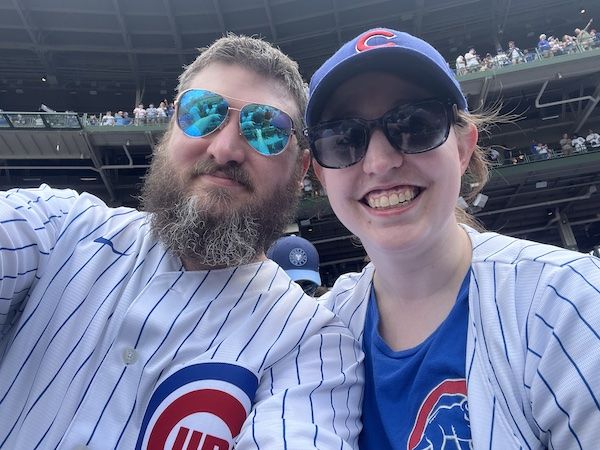a selfie of a smiling man and woman in Cubs jerseys