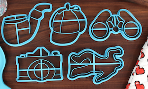 5 cookie cutters with shapes for mystery fans: a camera, a pipe, a body outline, binoculalrs, detective hat