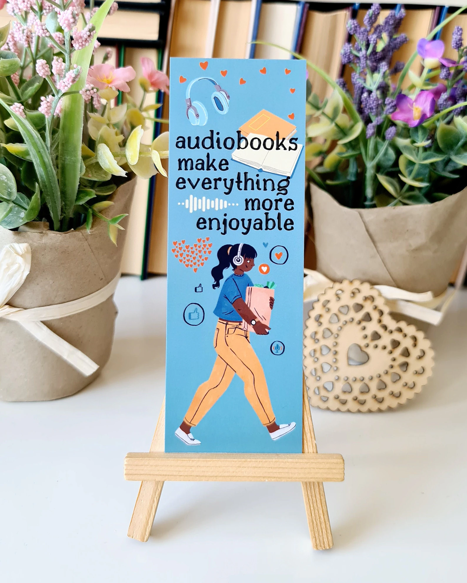 Image of a blue bookmark with a person listening to an audiobook and carrying groceries. It says "audiobooks make everything more enjoyable."