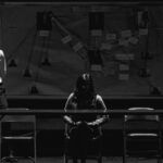 black and white photo of investigators in front of a crime board