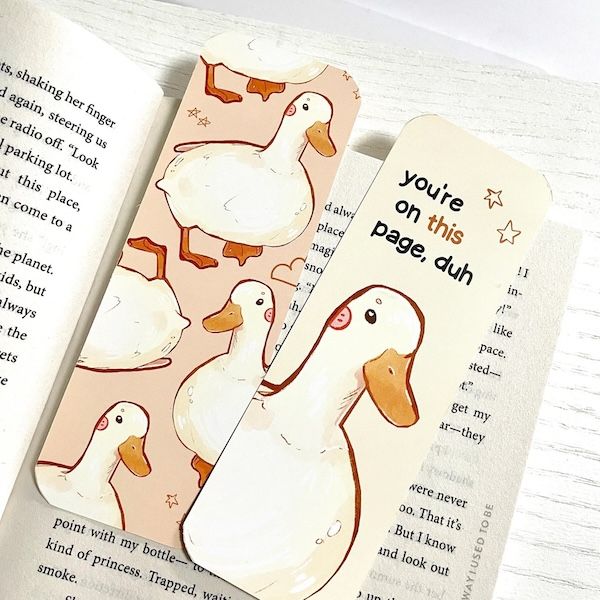 two bookmarks in an open book. the one on the left contains multiple drawings of ducks. the one on the right contains a single duck and text that reads "you're on this page, duh"